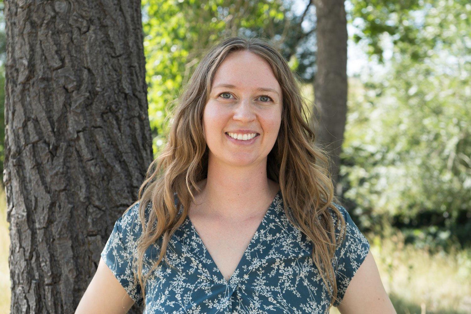 watershed project manager margo yousse stands smiling next to a tree